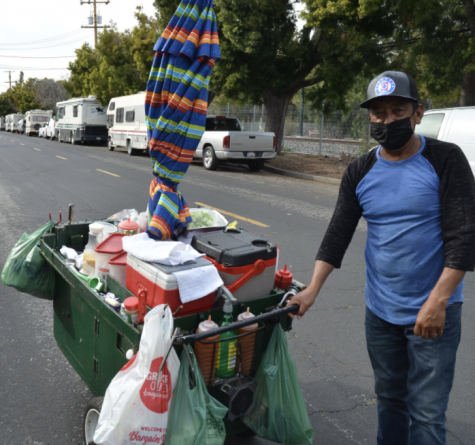 A seller stands with his cart on Crisanto street.  He has lived on the street for 25 years.